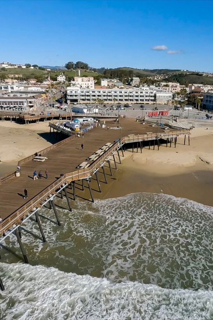 This may contain: people are walking on the beach near a pier that is being built into the water