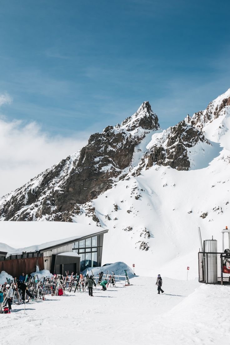 This may contain: skiers and snowboarders at the base of a snowy mountain