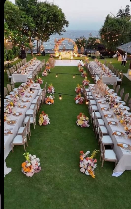 This may contain: an outdoor wedding setup with long tables and chairs set up for the guests to sit down