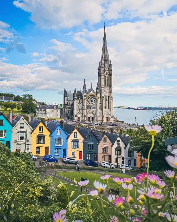 This may contain: colorful houses in front of a large cathedral