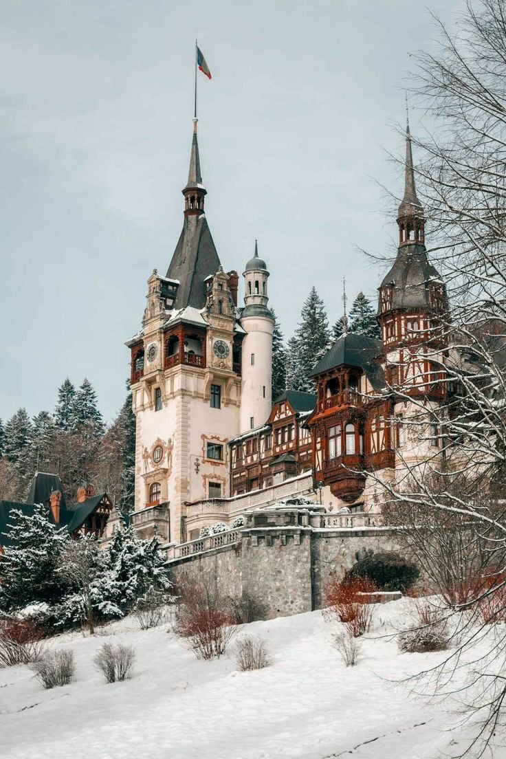 This may contain: an old castle in the middle of winter with snow on the ground and trees around it