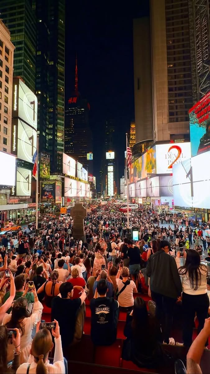 This may contain: a large group of people sitting in the middle of a city street at night time