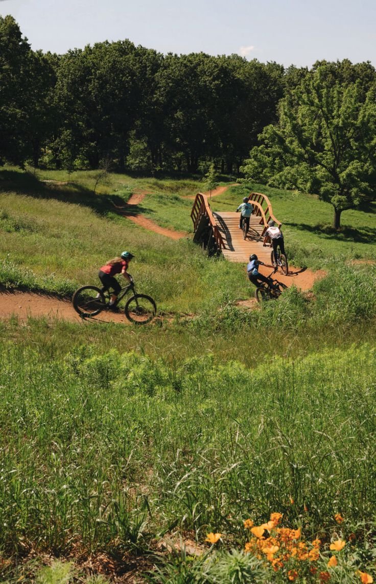This may contain: several people riding bikes on a dirt trail