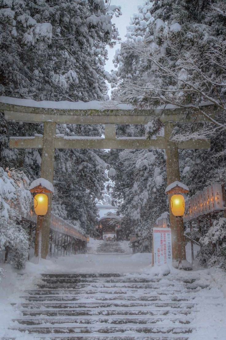 This may contain: a snow covered path leading to a shrine