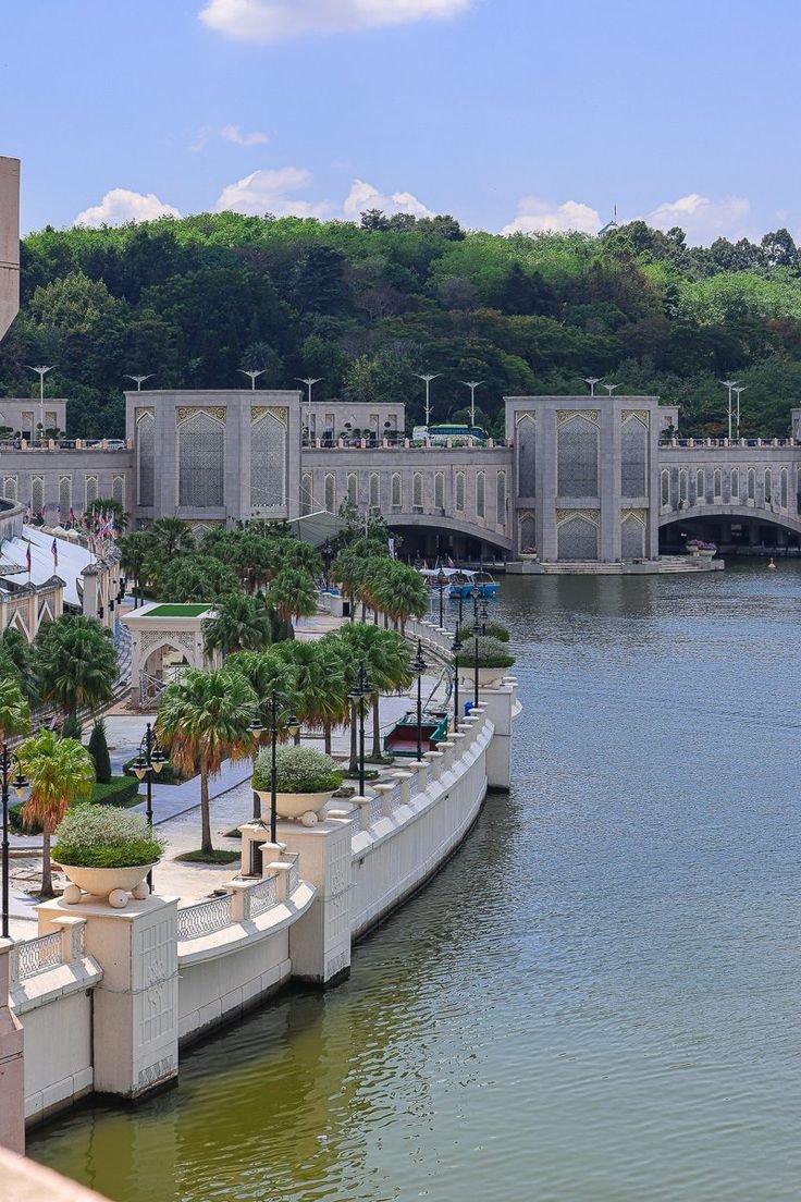 This may contain: there are many palm trees on the side of the river bank and buildings in the background