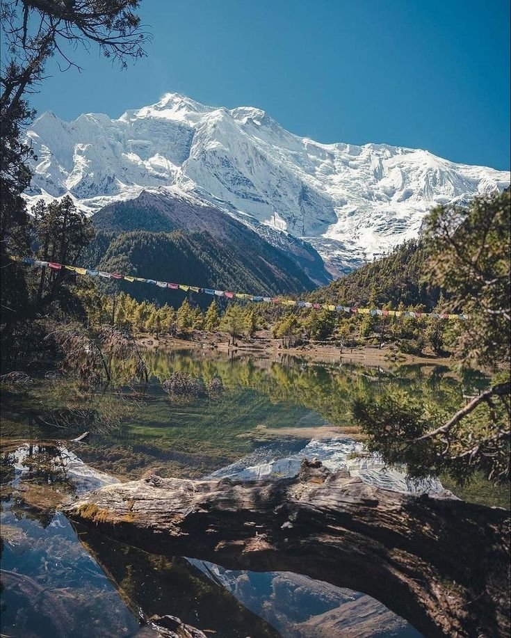 This may contain: the snow covered mountain is reflected in the still water