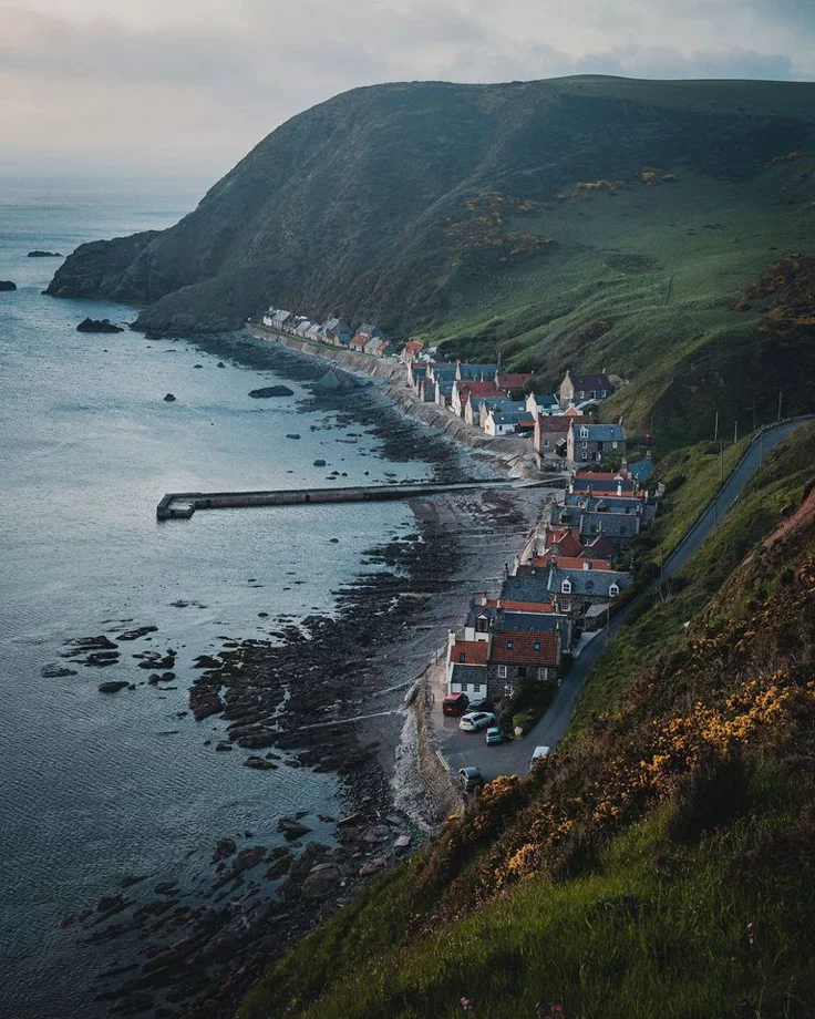 This may contain: an aerial view of the coastline with houses on it and mountains in the back ground