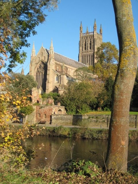 This may contain: an old cathedral is next to a body of water with trees in the foreground