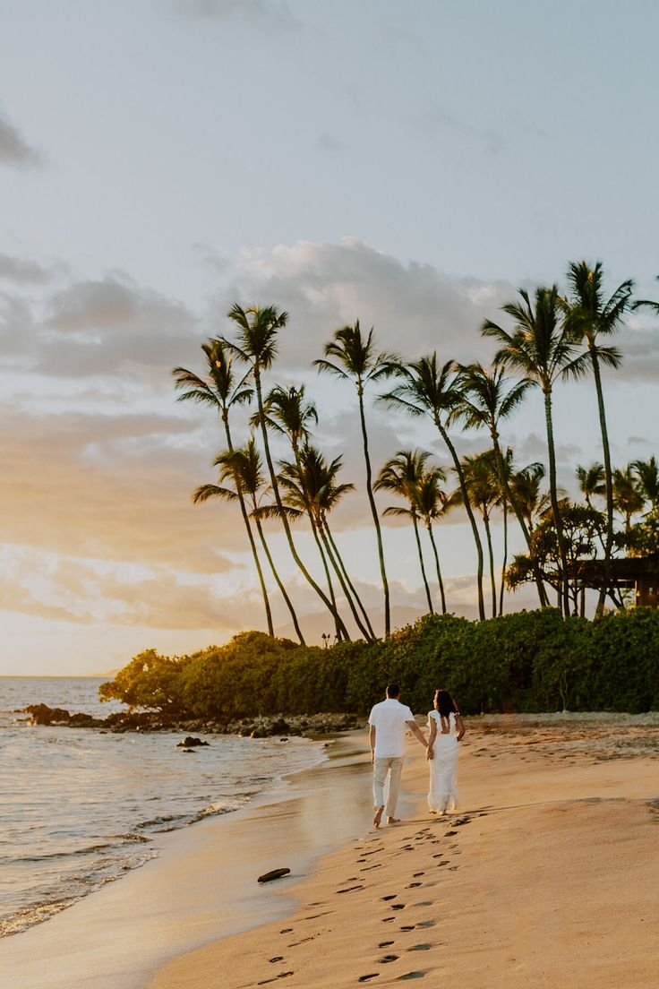 This may contain: a man and woman walking on the beach with palm trees in the background at sunset