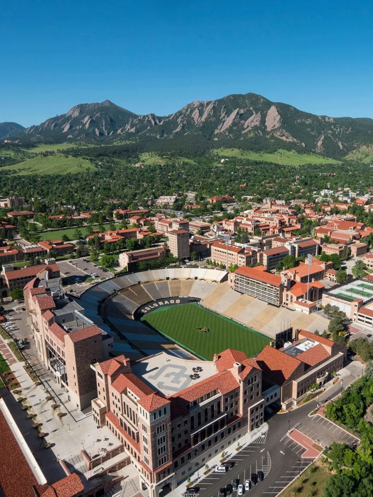 This may contain: an aerial view of a baseball stadium and surrounding buildings with mountains in the back ground