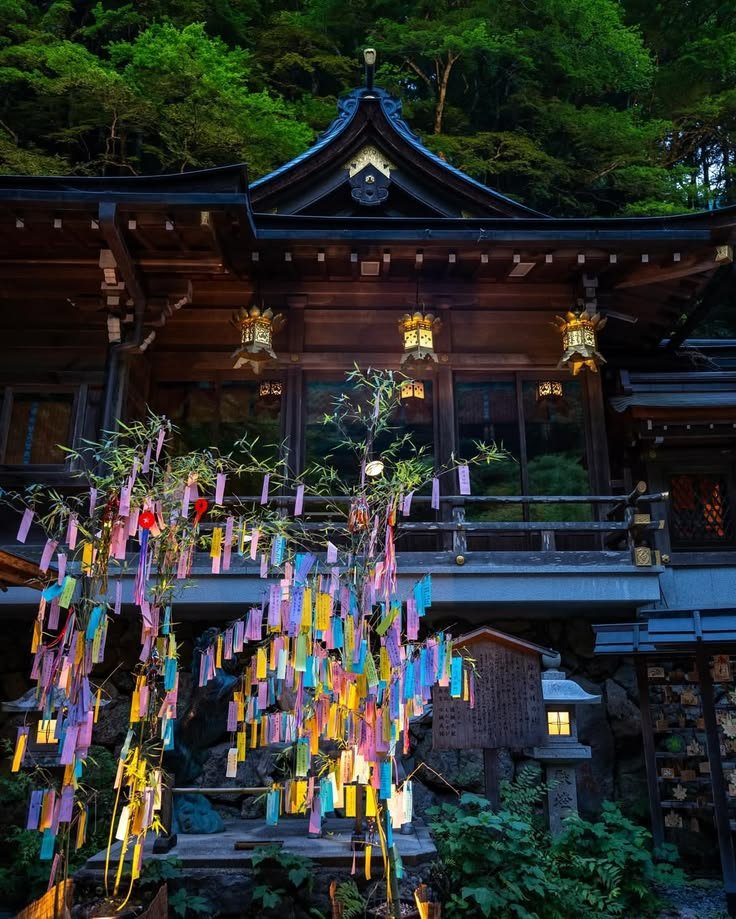 This may contain: a building with many lights hanging from it's roof and trees in the background
