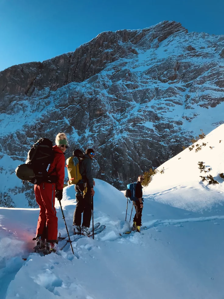 This may contain: three people on skis stand at the top of a snowy hill with mountains in the background