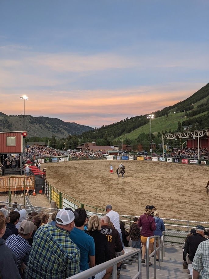 This may contain: people are watching a horse race in an arena with mountains in the backgroud