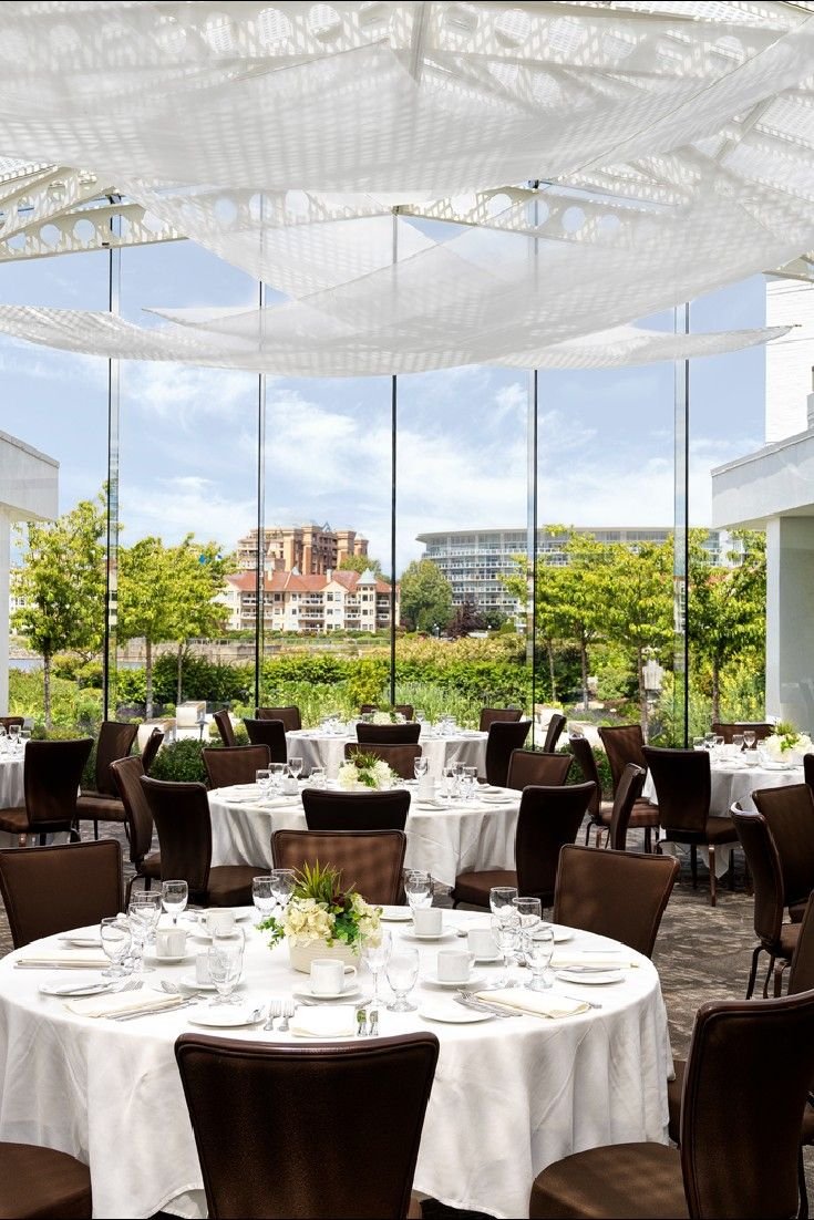 This may contain: an indoor dining area with tables, chairs and umbrellas over looking the cityscape