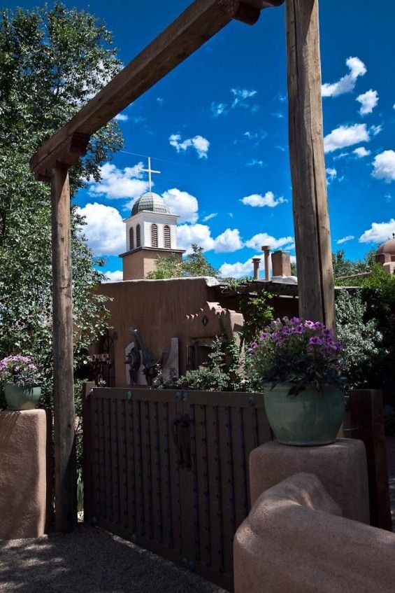 This may contain: a building with a clock tower in the background and purple flowers growing on the fence