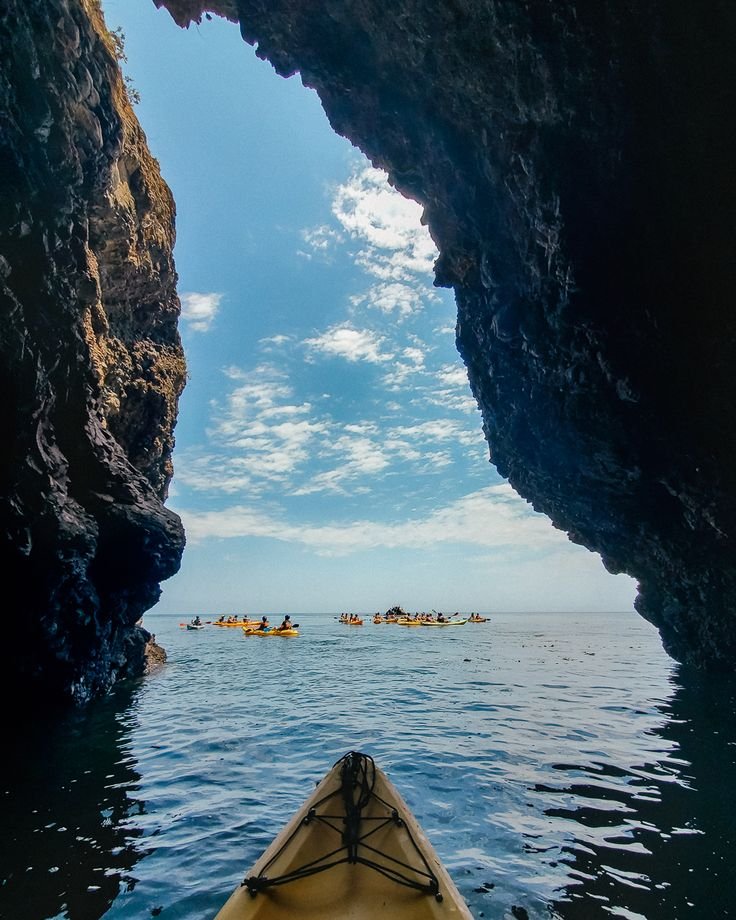 This may contain: a kayak is in the middle of an ocean with people paddling through it