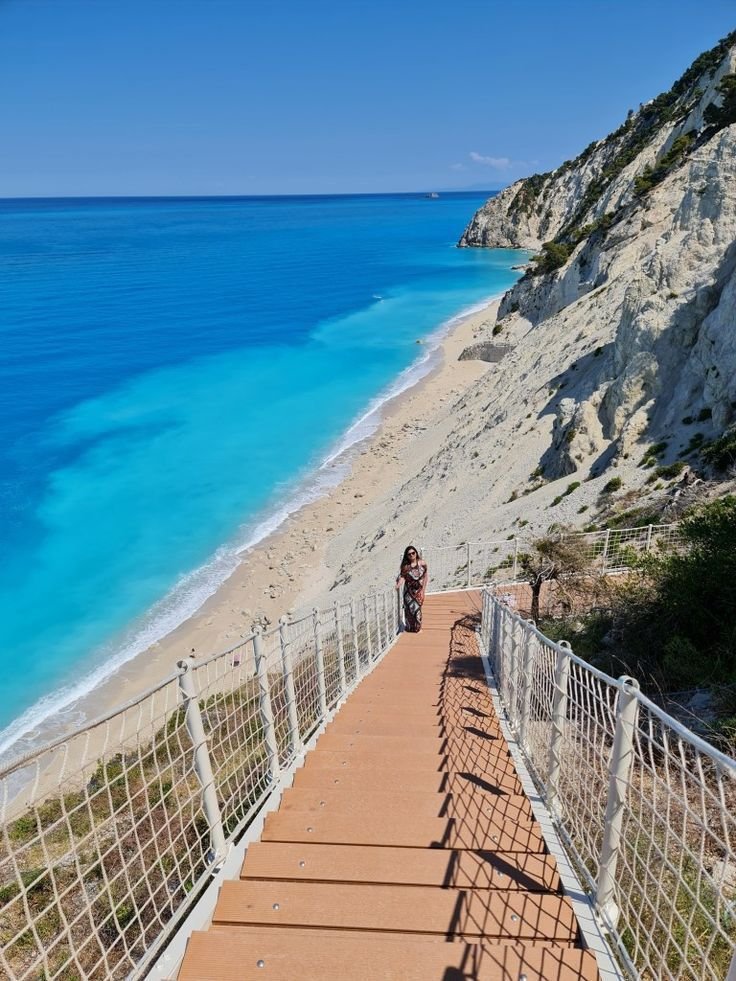 This may contain: a person walking down stairs to the beach