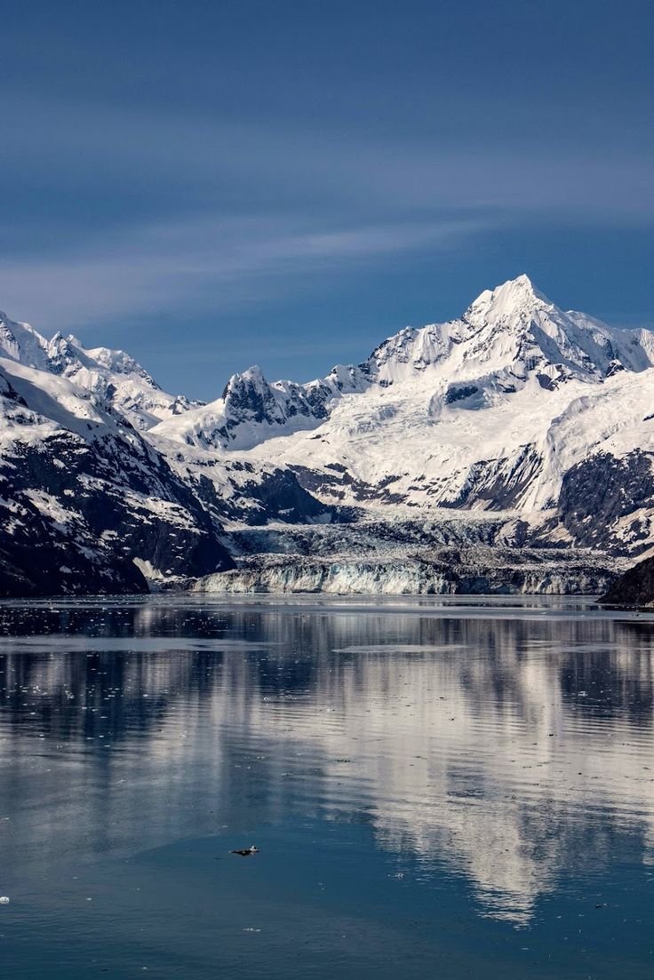 This may contain: the mountains are covered in snow and ice as they reflect on the water's surface
