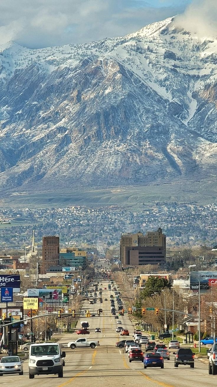 This may contain: cars are driving down the road with mountains in the background