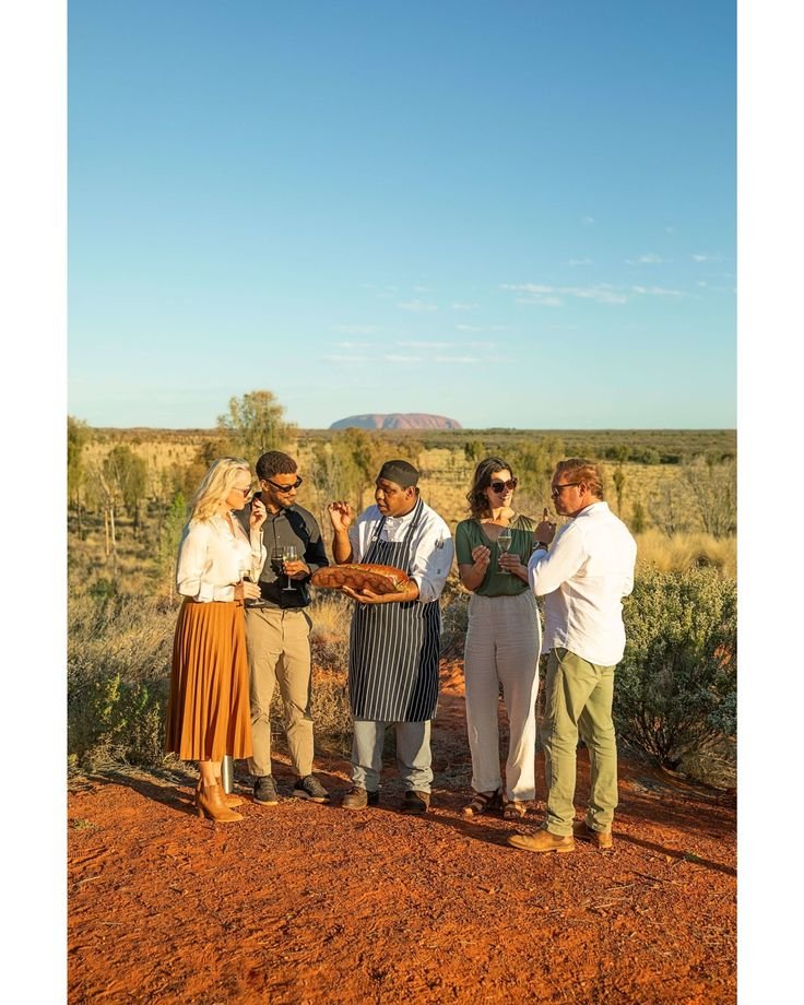 This may contain: four people are standing in the dirt with a plate on their lap and one person is holding something