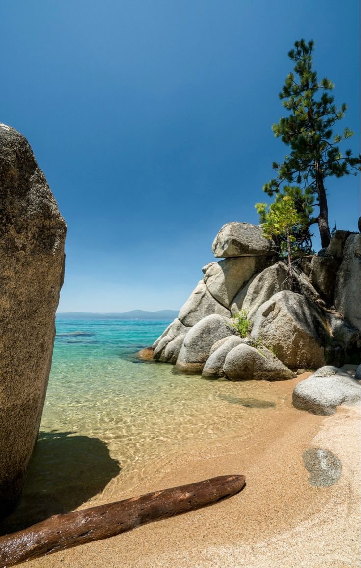 This may contain: a large rock sitting on top of a sandy beach
