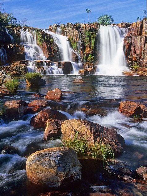 This may contain: the waterfall is surrounded by large rocks and water cascading down it's sides