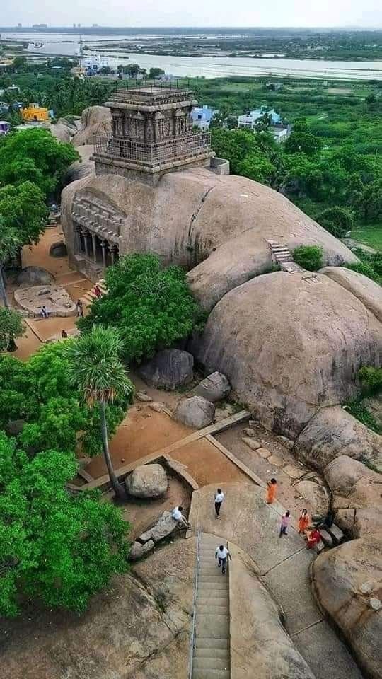 This may contain: people walking up and down steps in front of large rock formations with trees on each side
