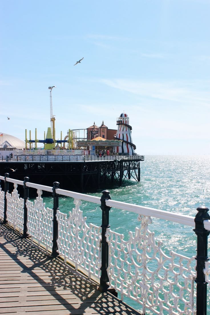 This may contain: the pier is next to the ocean with people on it