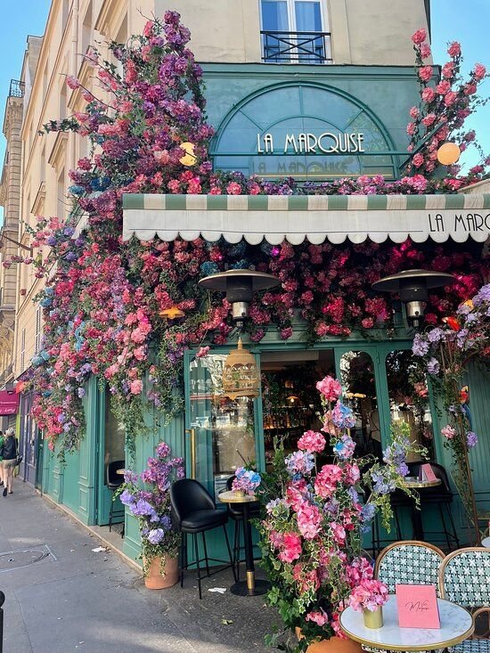 This may contain: the outside of a flower shop with lots of flowers growing on it's side