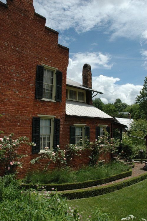 This may contain: an old brick house surrounded by greenery and flowers