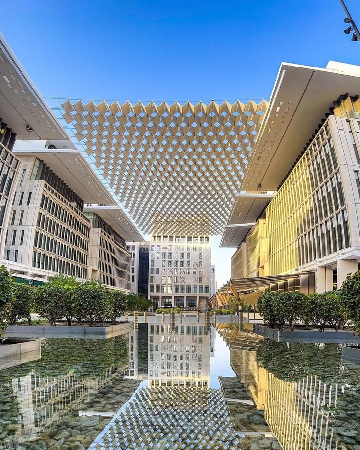 This may contain: the reflection of buildings in the water is seen on the glass floored pool at the entrance to the building
