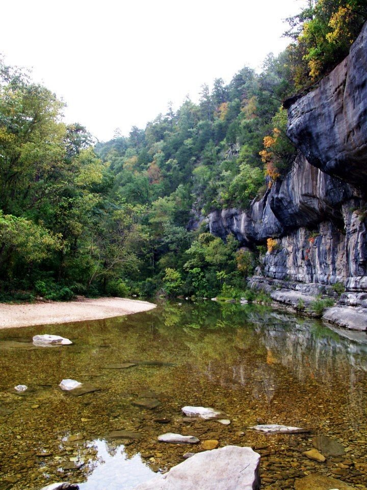 This may contain: a river with rocks and trees in the background