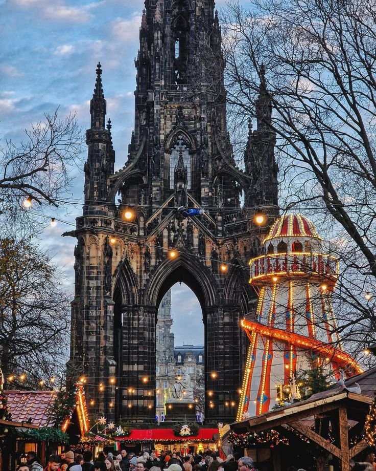This may contain: people are walking around in front of an old building with christmas lights and decorations on it