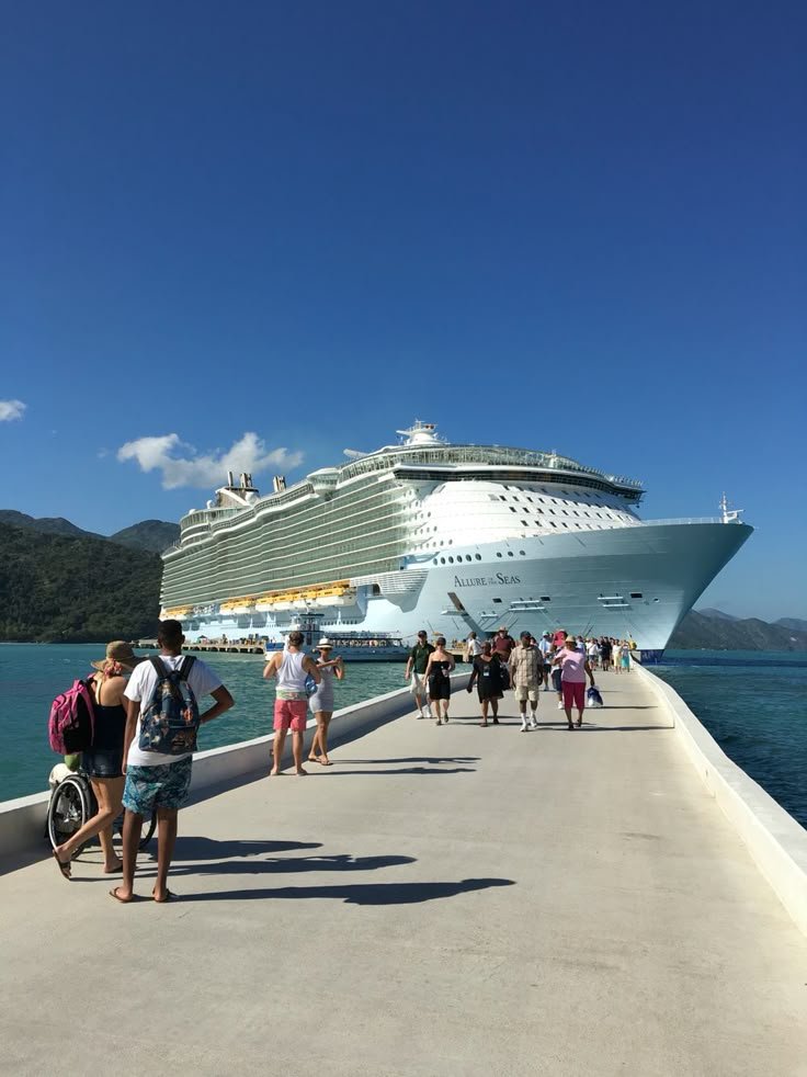 This may contain: people are walking on the pier next to a cruise ship