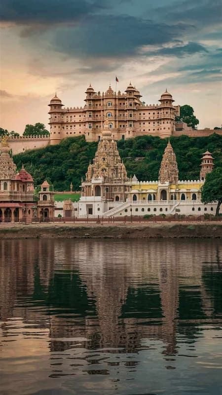 This may contain: an ornate building on top of a hill next to the water