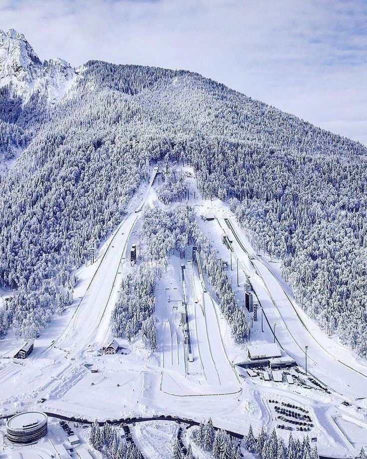 This may contain: an aerial view of a ski resort in the mountains with snow on the ground and trees around it