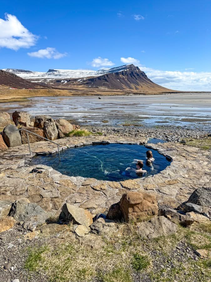 This may contain: an outdoor hot tub surrounded by rocks and water