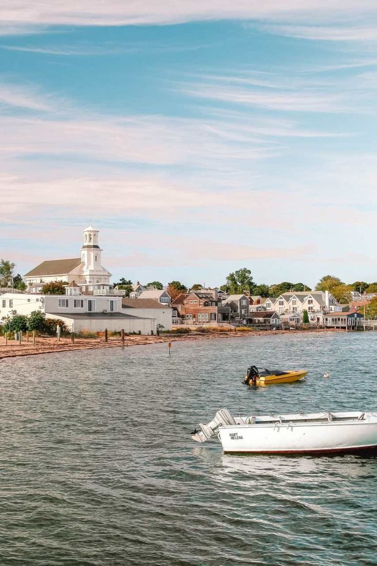 This may contain: two small boats in the water near a shore line with houses and buildings behind them
