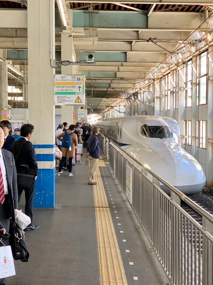 This may contain: people are waiting on the platform to board a high speed train at an indoor station