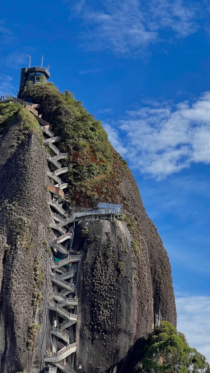This may contain: a very tall mountain with a spiral staircase going up it's side to the top