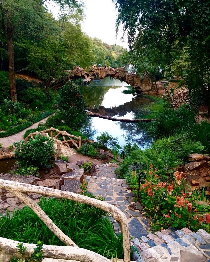 This may contain: a stone path leading to a river surrounded by greenery
