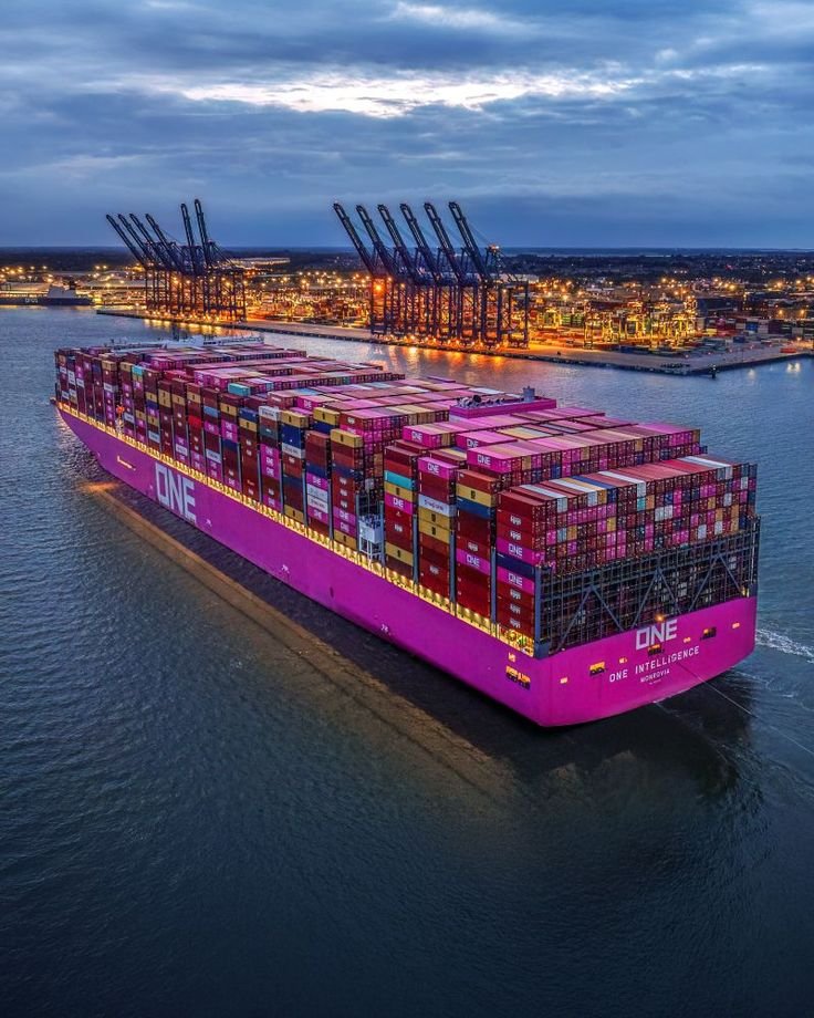This may contain: a large pink container ship in the water at night with its lights on and cargo containers all around it