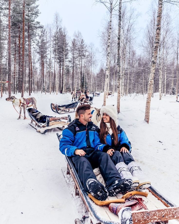 This may contain: a man and woman sitting on sleds in the snow next to each other
