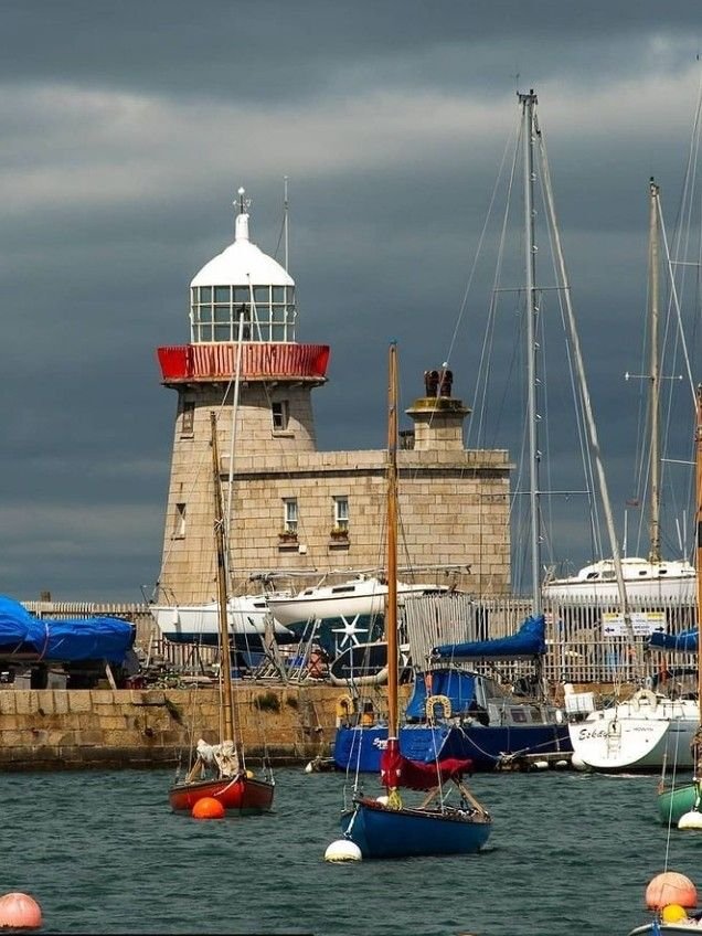 This may contain: several sailboats are in the water near a light house and dock with other boats