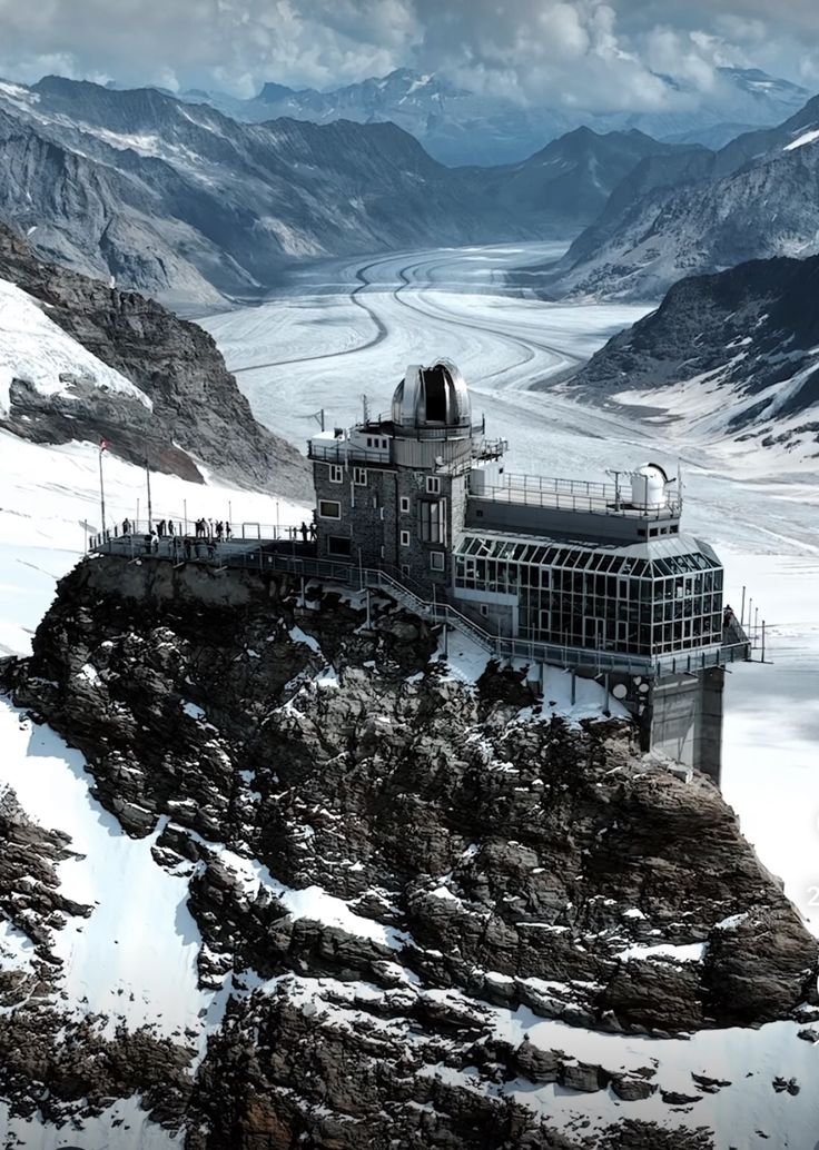 This may contain: a large building sitting on top of a snow covered mountain next to a glacier filled with mountains