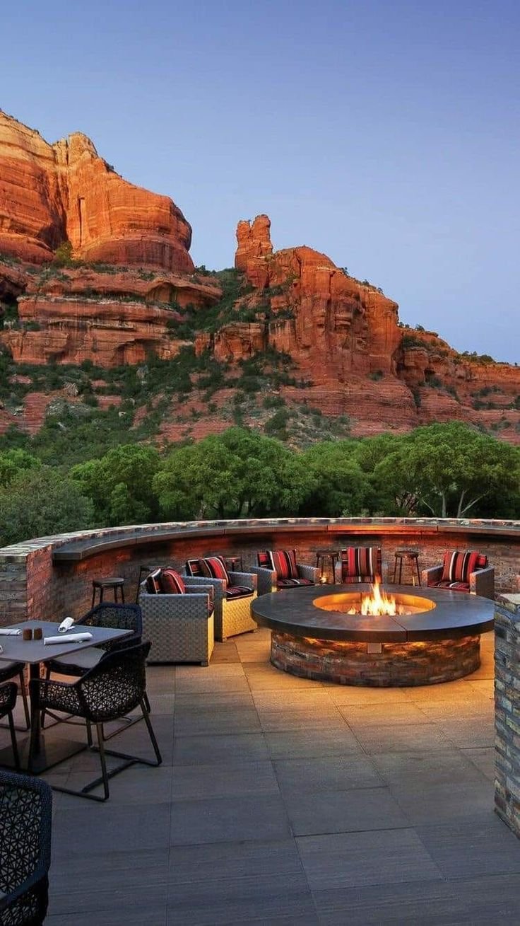 This may contain: an outdoor fire pit surrounded by chairs and tables