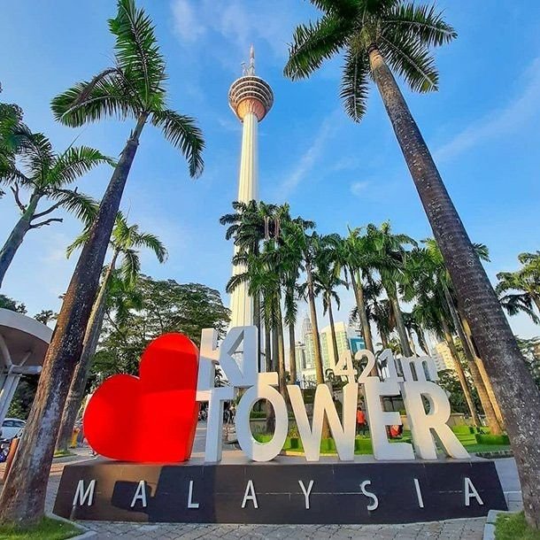 This may contain: the sign is in front of palm trees and a tall tower with a red heart