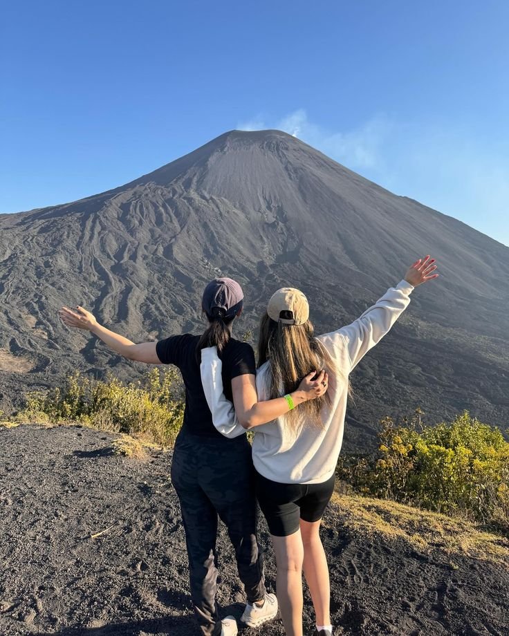 This may contain: two people standing on top of a mountain with their arms spread out in the air