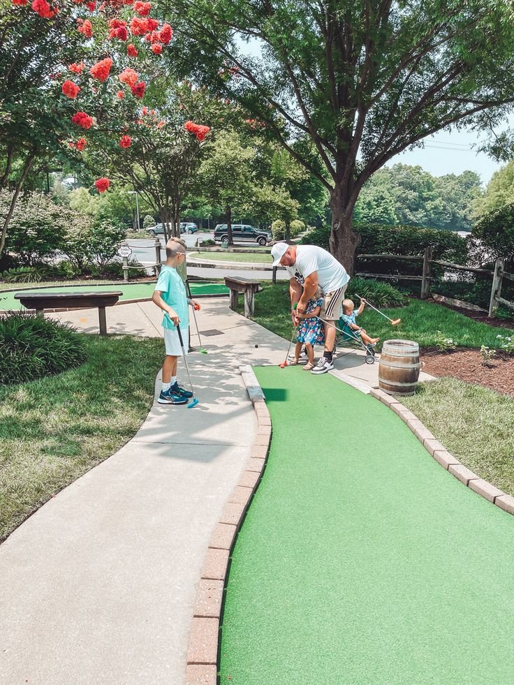 This may contain: an older man and young boy playing miniature golf