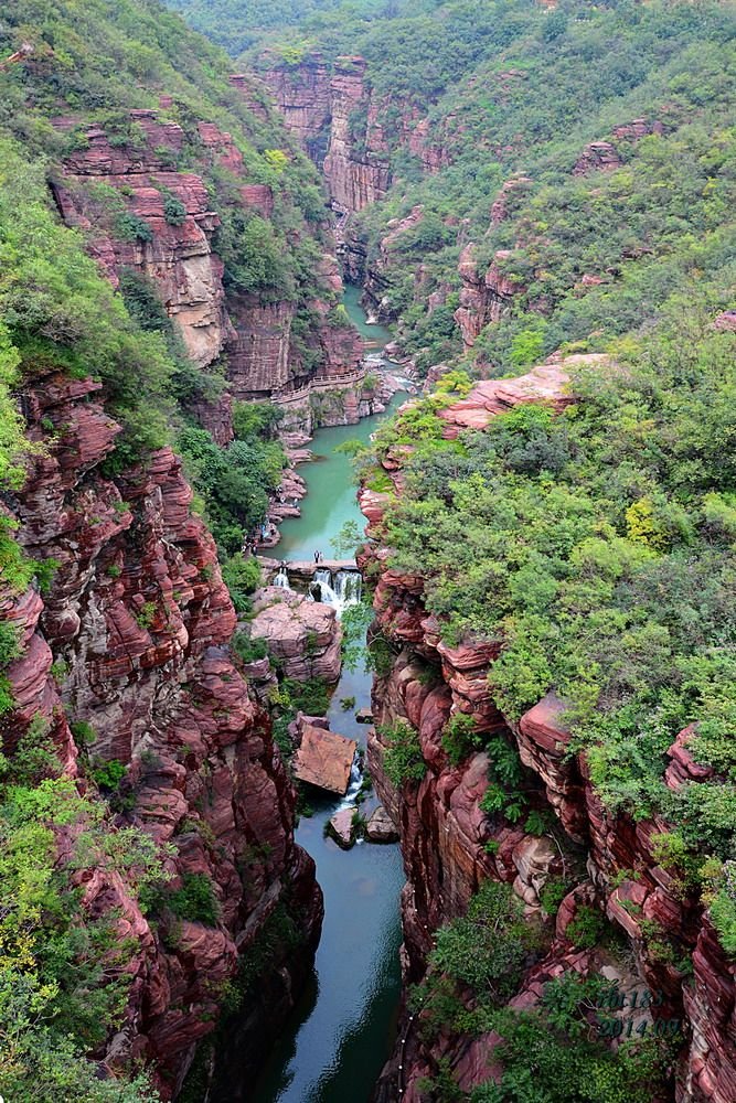 This may contain: a river flowing through a lush green forest filled valley next to tall rocky cliffs covered in greenery